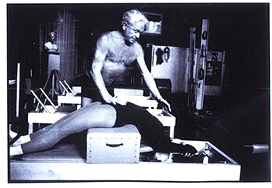 Joseph Pilates auxiliando uma aluna no Reformer
