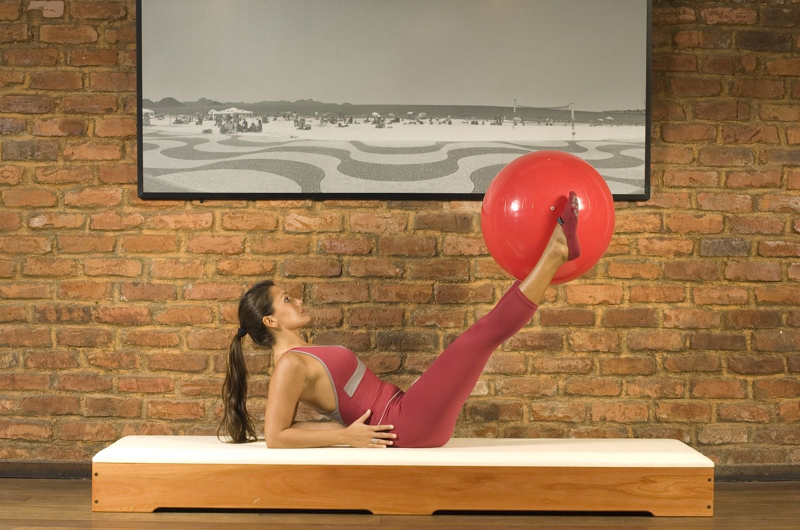 Aluna praticando exercício com bola vermelha no studio Metacorpus